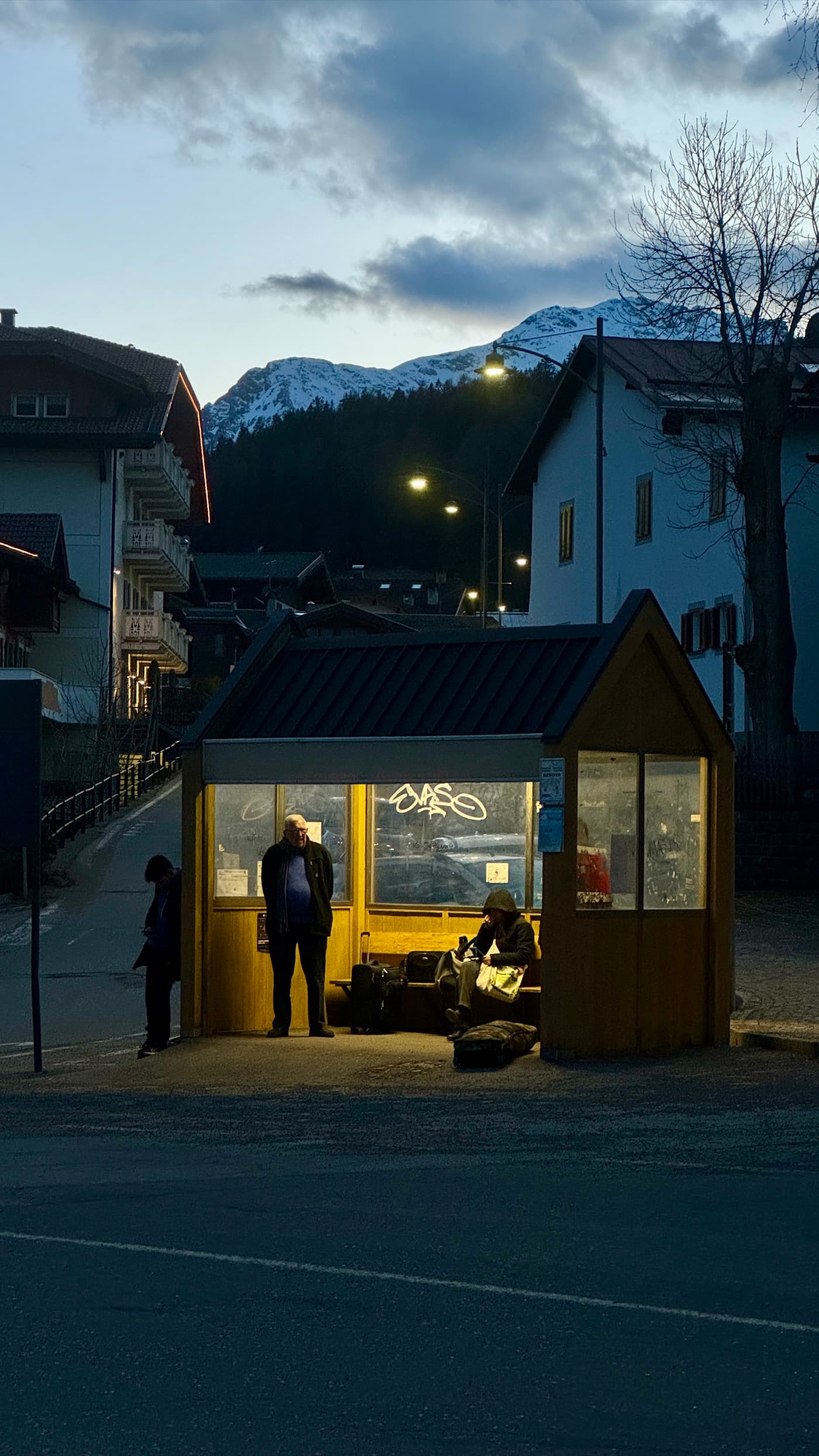 A warmly lit roadside shelter at dusk in the Dolomites
