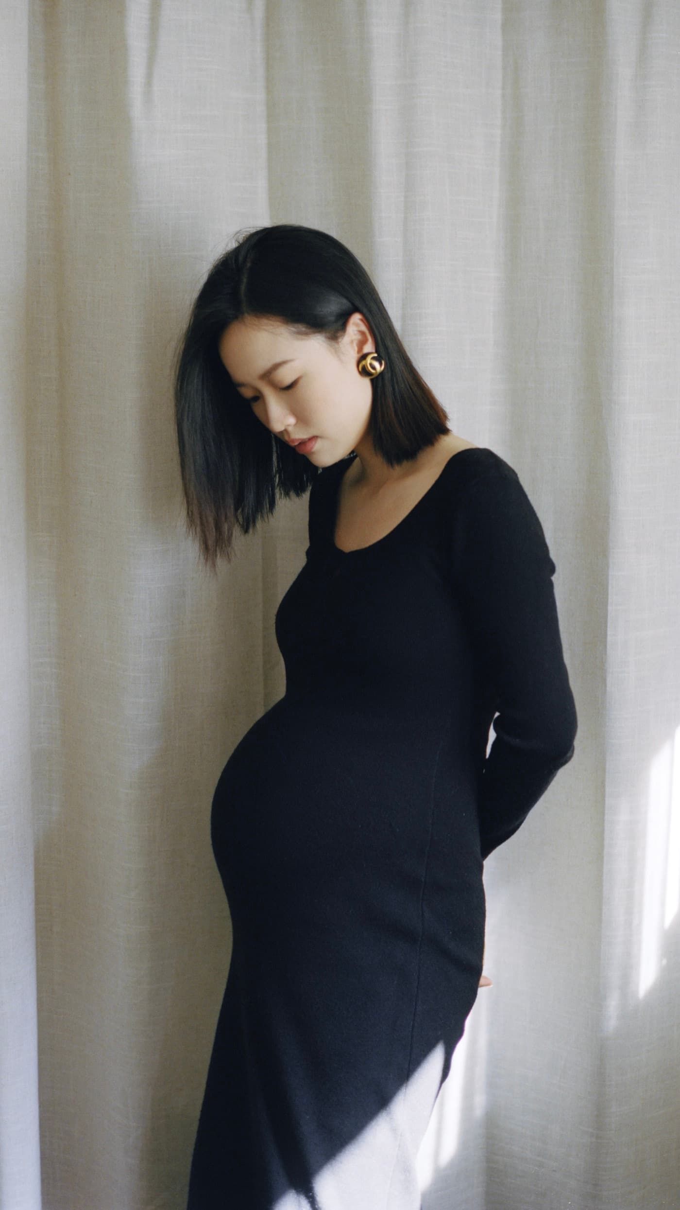 A pregnancy portrait of Wentian in a black dress by a window