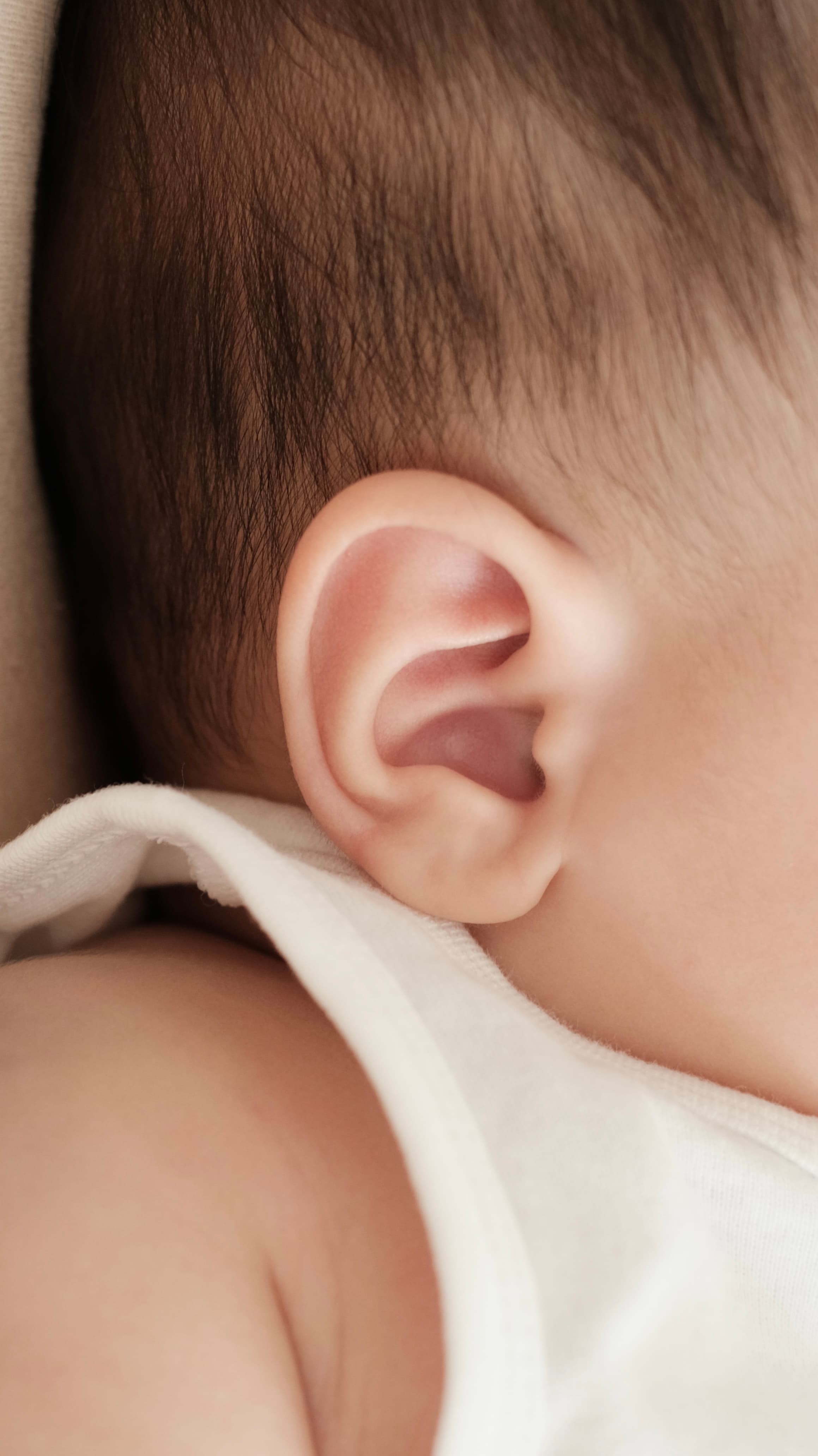 A close-up glimpse of a baby’s ear and shoulder