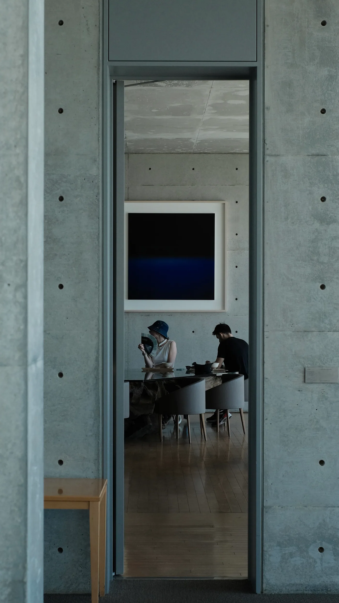 Two visitors framed by a doorway in a concrete building